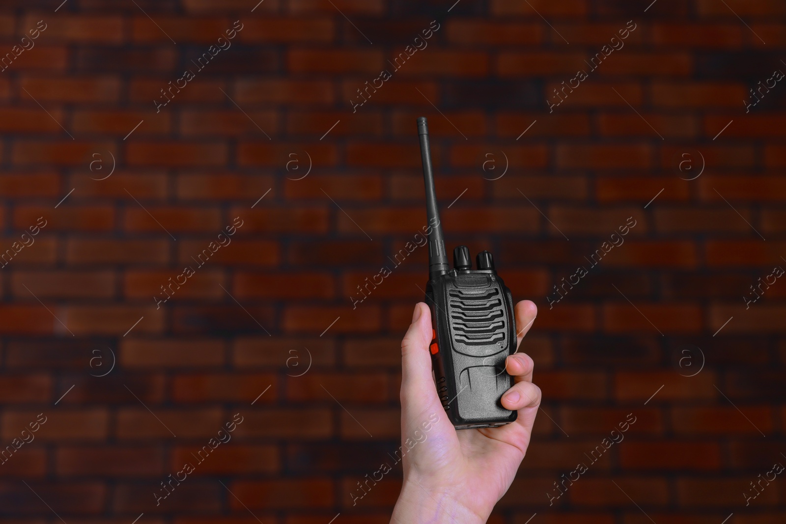 Photo of Woman with walkie talkie against brick wall, closeup. Space for text