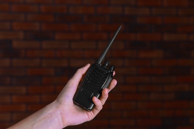 Photo of Woman with walkie talkie against brick wall, closeup