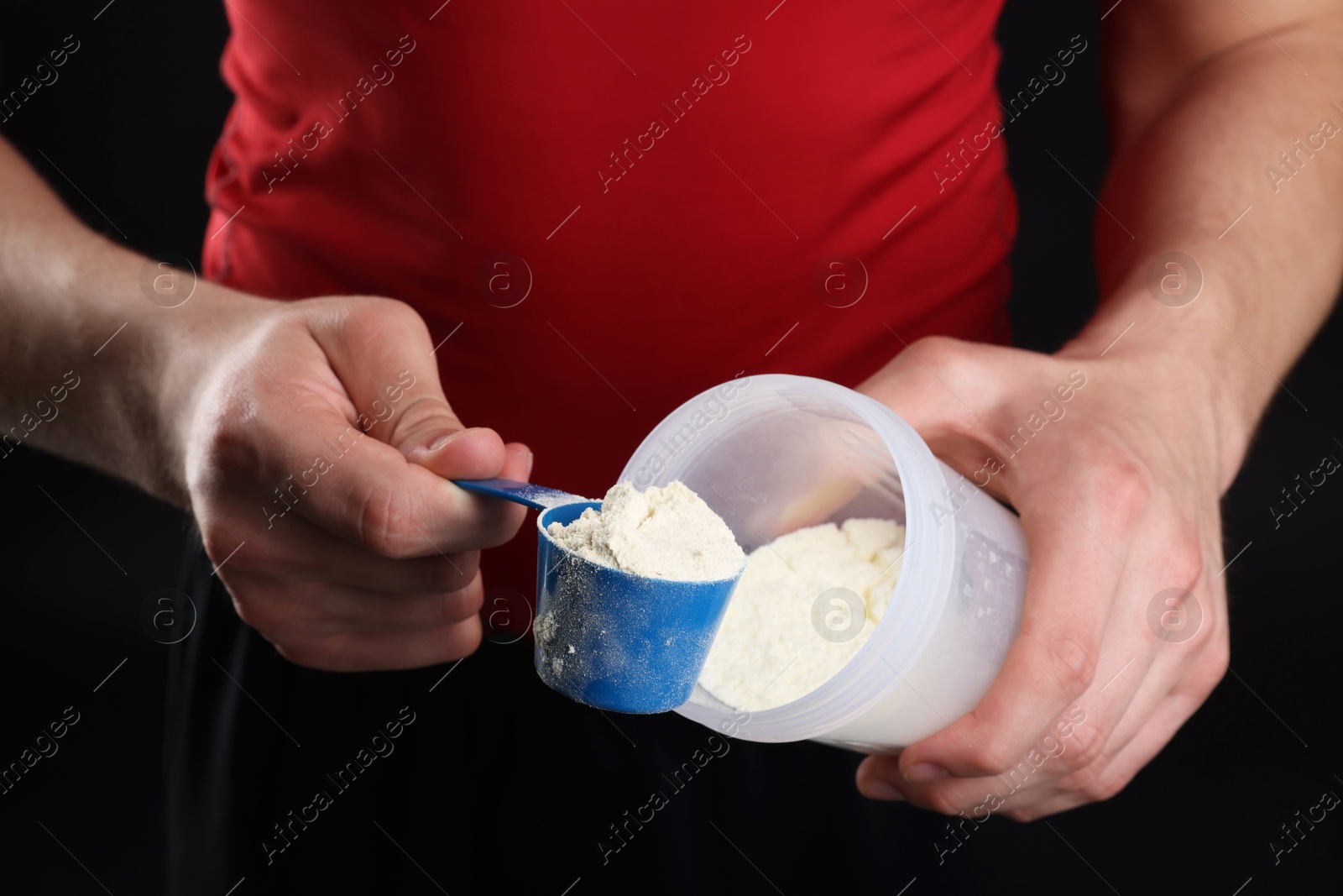 Photo of Sportsman adding protein into shaker on dark background, closeup