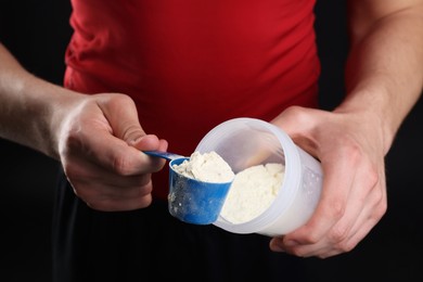 Sportsman adding protein into shaker on dark background, closeup