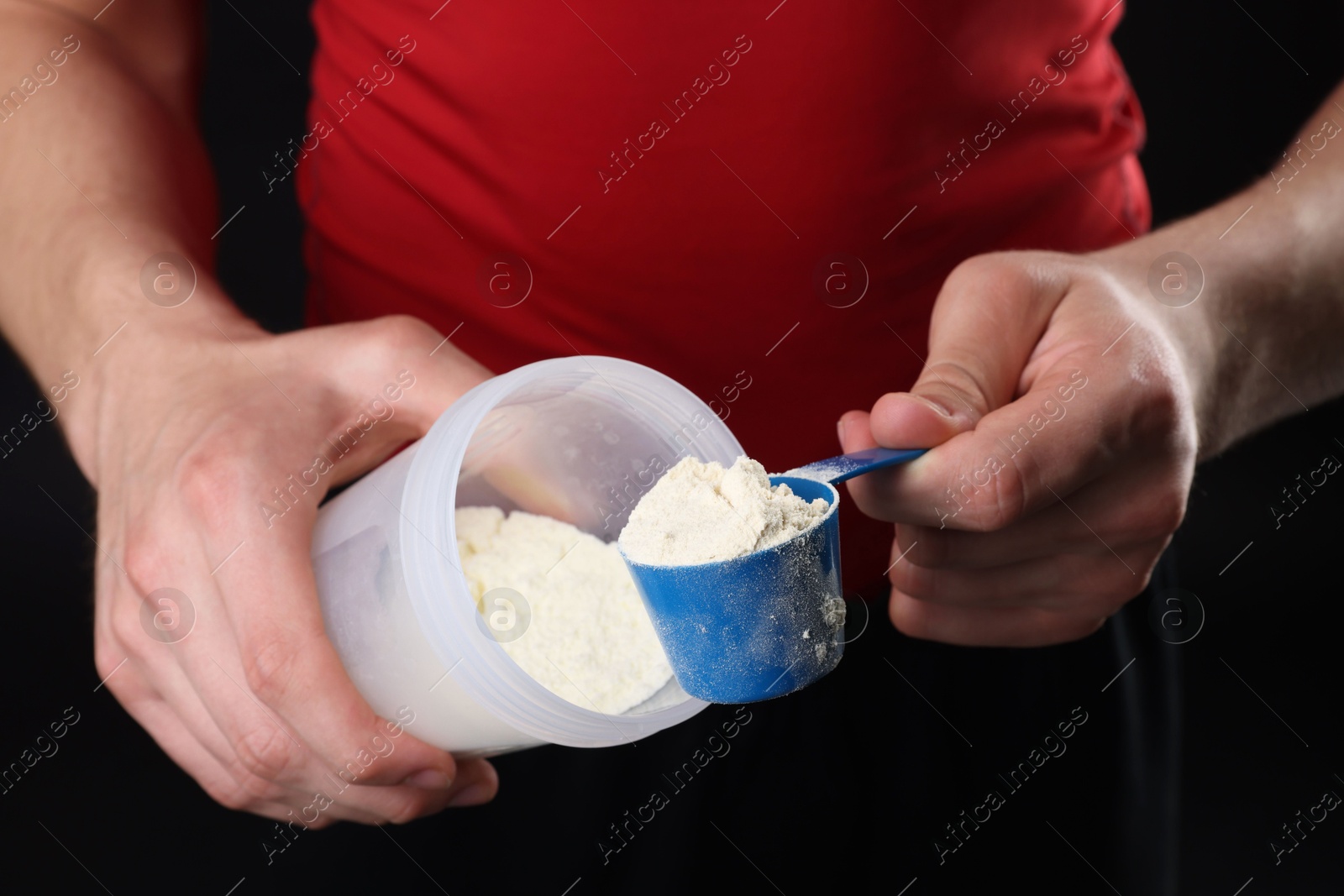 Photo of Sportsman adding protein into shaker on dark background, closeup