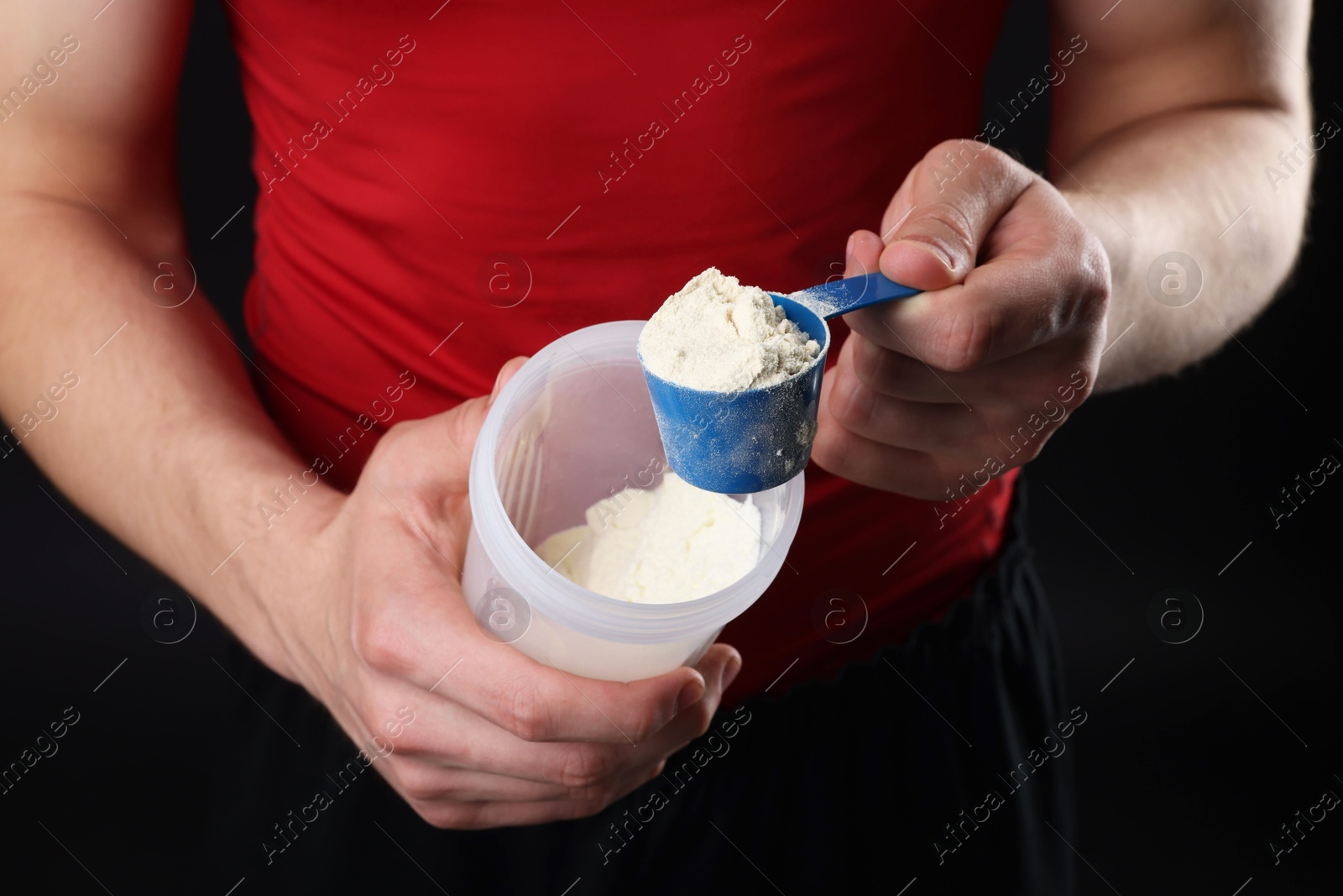 Photo of Sportsman adding protein into shaker on dark background, closeup