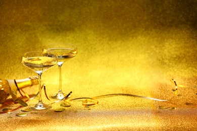 Photo of Champagne, confetti and streamers on golden background. Space for text