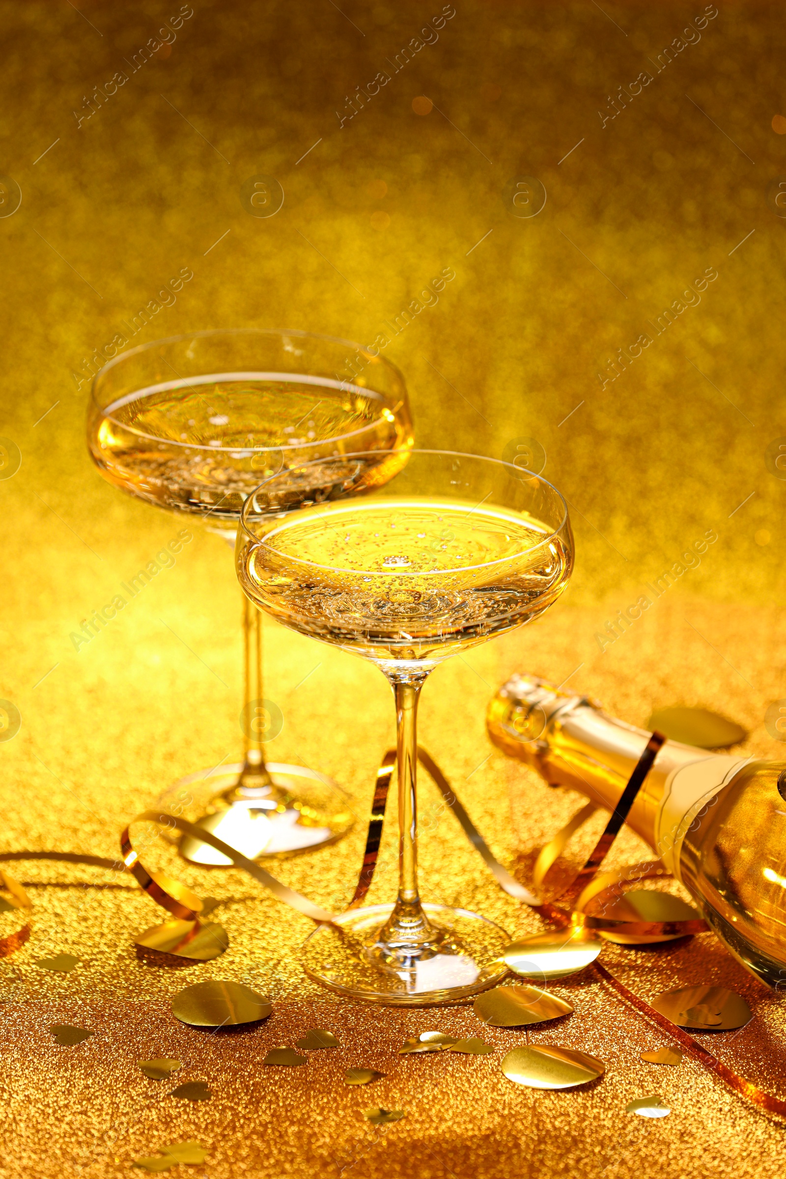 Photo of Champagne, confetti and streamers on golden background