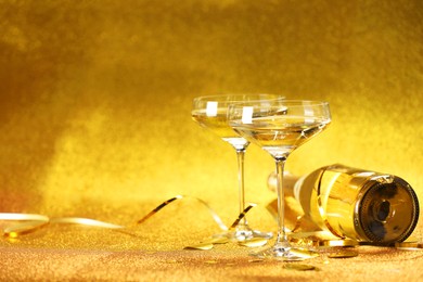 Photo of Champagne, confetti and streamers on golden background. Space for text