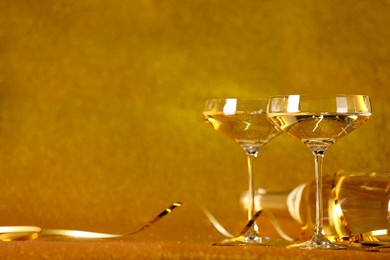 Photo of Champagne in glasses and bottle on golden background. Space for text