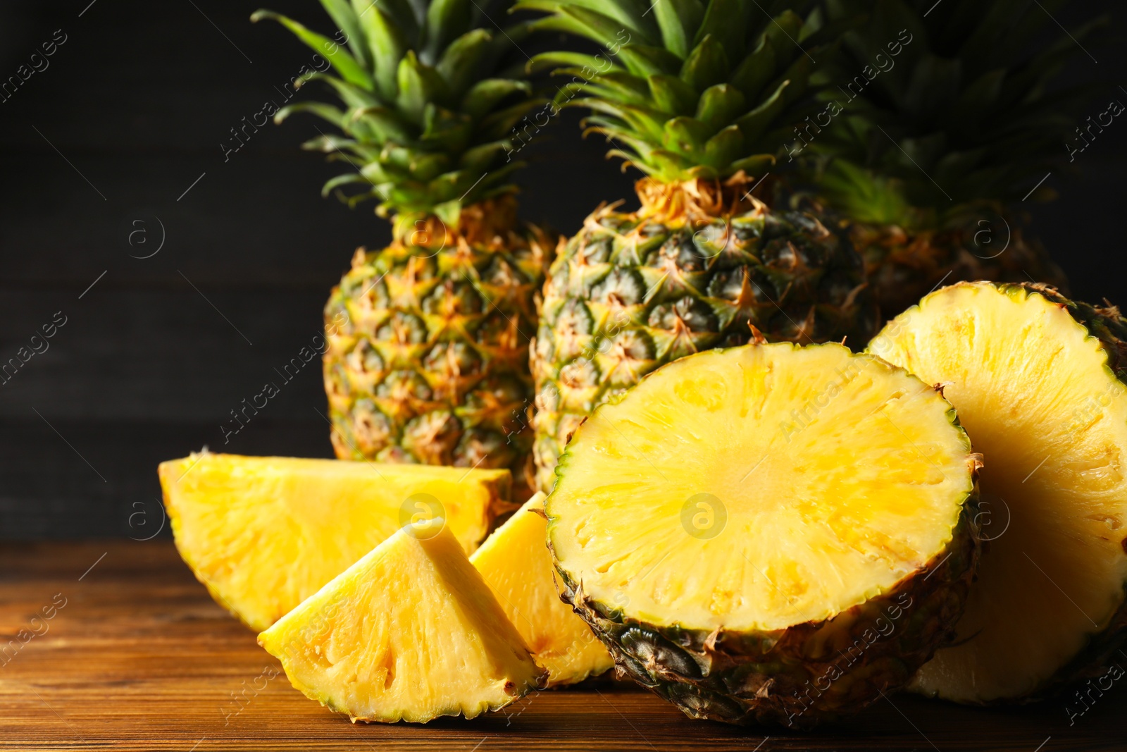 Photo of Whole and cut ripe pineapples on wooden table