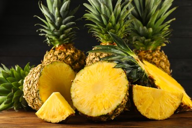 Photo of Whole and cut ripe pineapples on wooden table