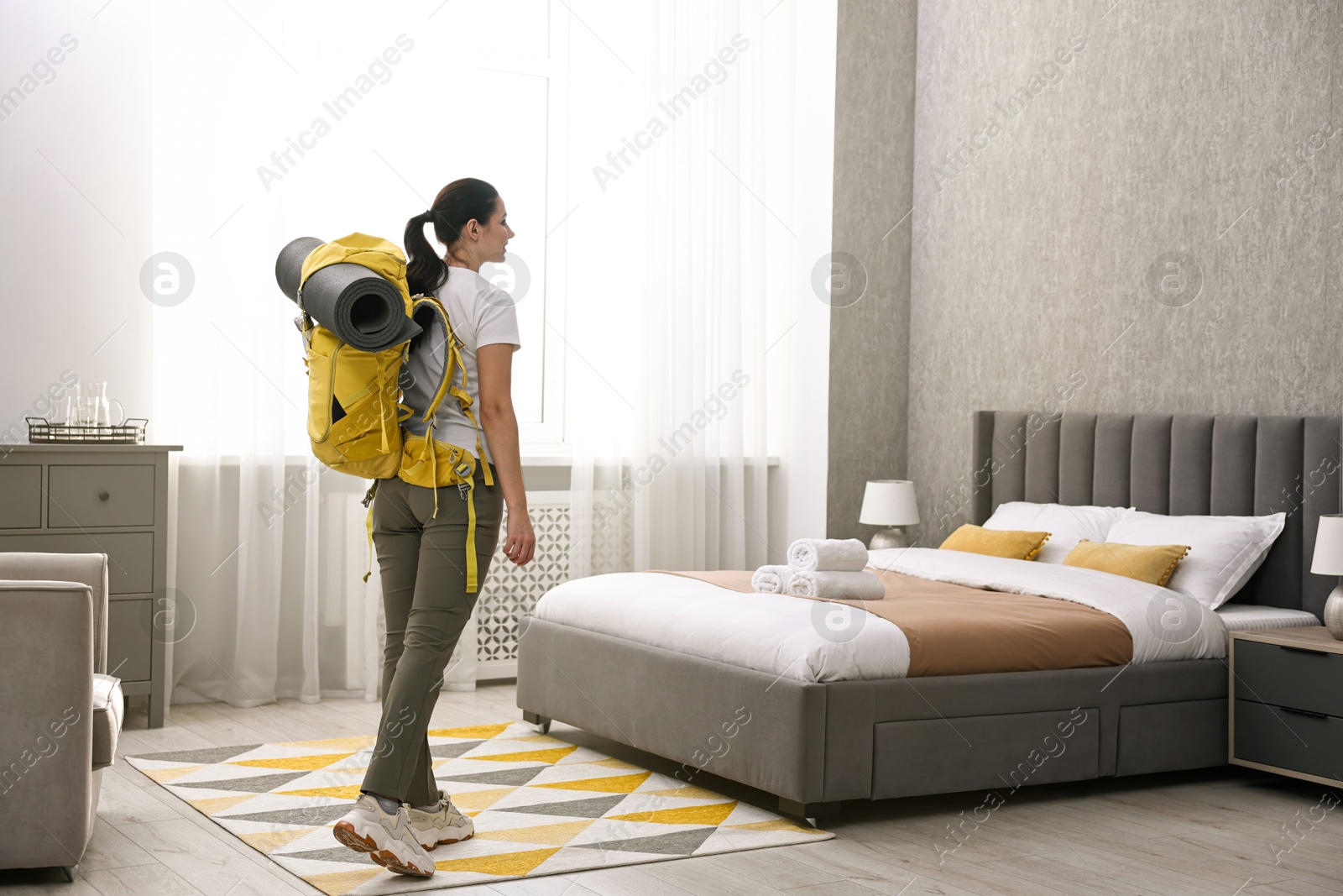 Photo of Traveller with backpack near bed in hotel room