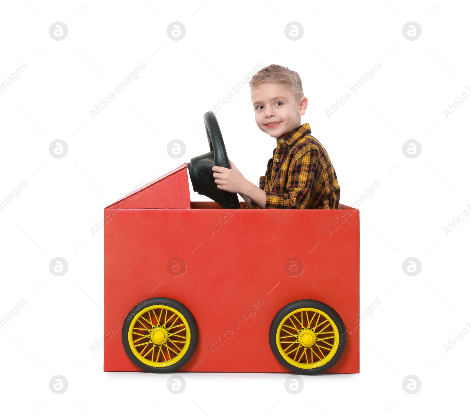 Photo of Little boy driving car made of cardboard on white background