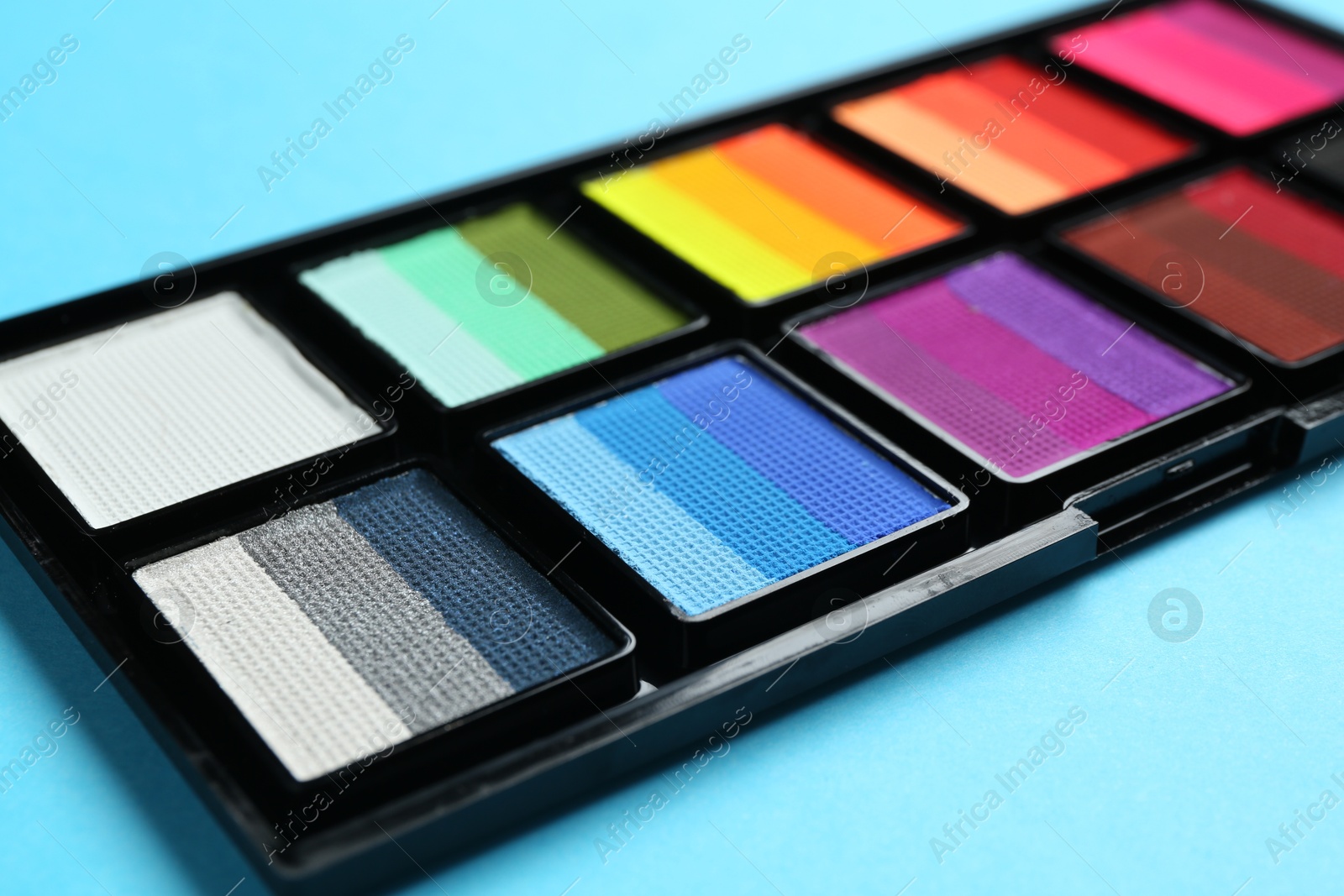 Photo of Bright face paints on light blue background, closeup