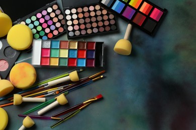 Photo of Bright face paints, brushes and sponges on color background, flat lay. Space for text