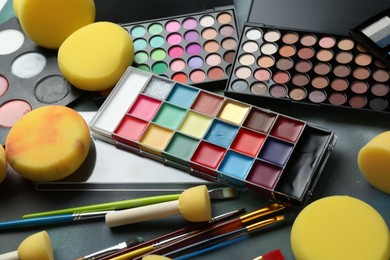 Photo of Bright face paints, brushes and sponges on color background