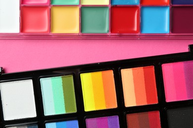 Photo of Bright face paints on pink background, top view