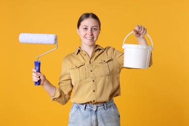 Photo of Woman with roller and bucket of paint on orange background