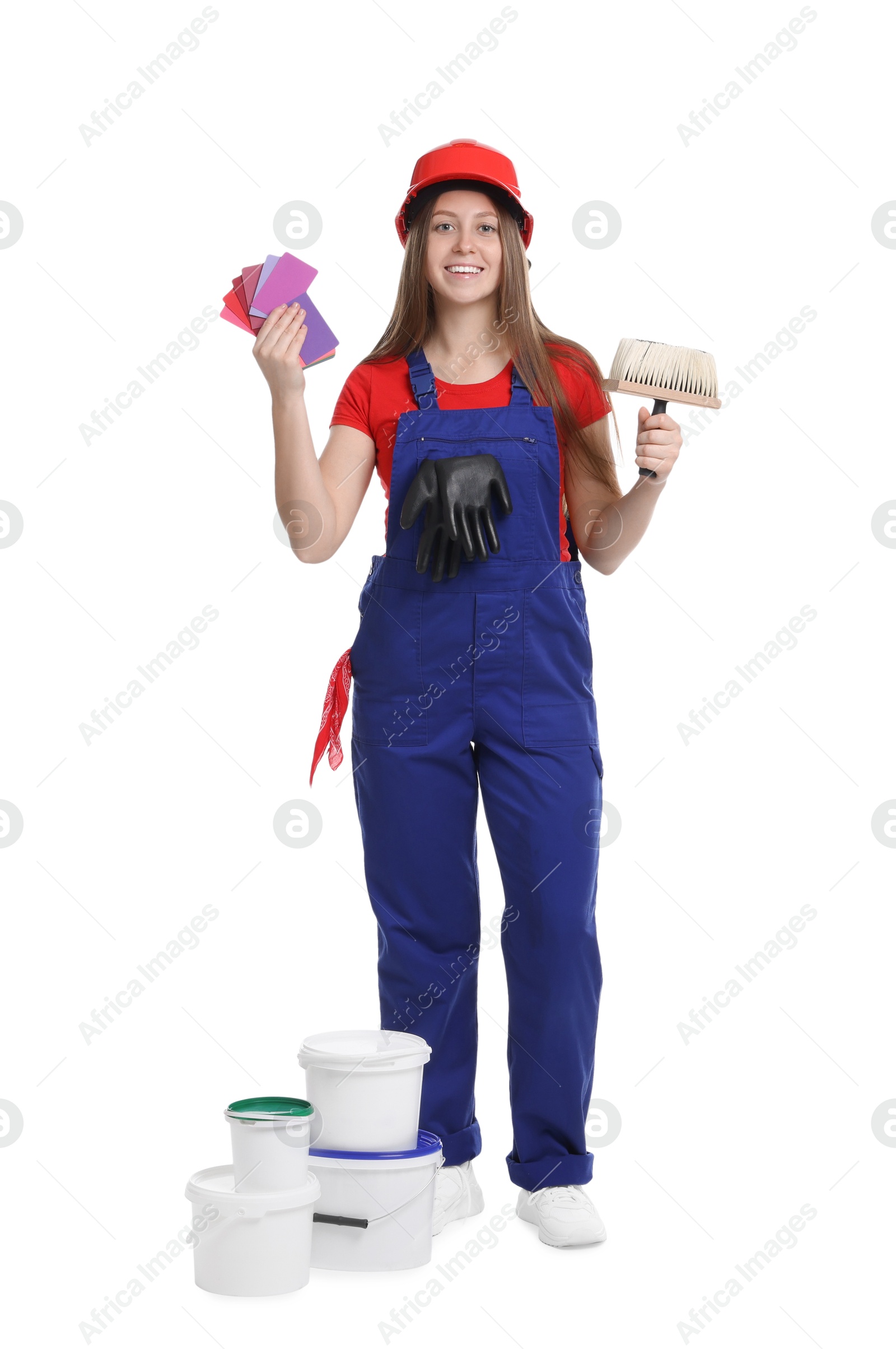 Photo of Professional painter with brush, color samples and buckets of paint on white background