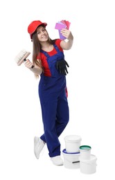 Photo of Professional painter with brush, color samples and buckets of paint on white background