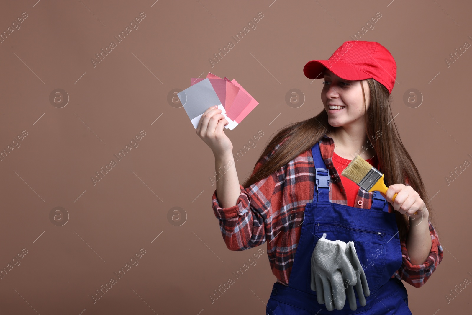 Photo of Professional painter with brush and color samples on brown background. Space for text