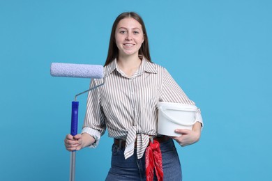 Photo of Woman with roller and bucket of paint on light blue background