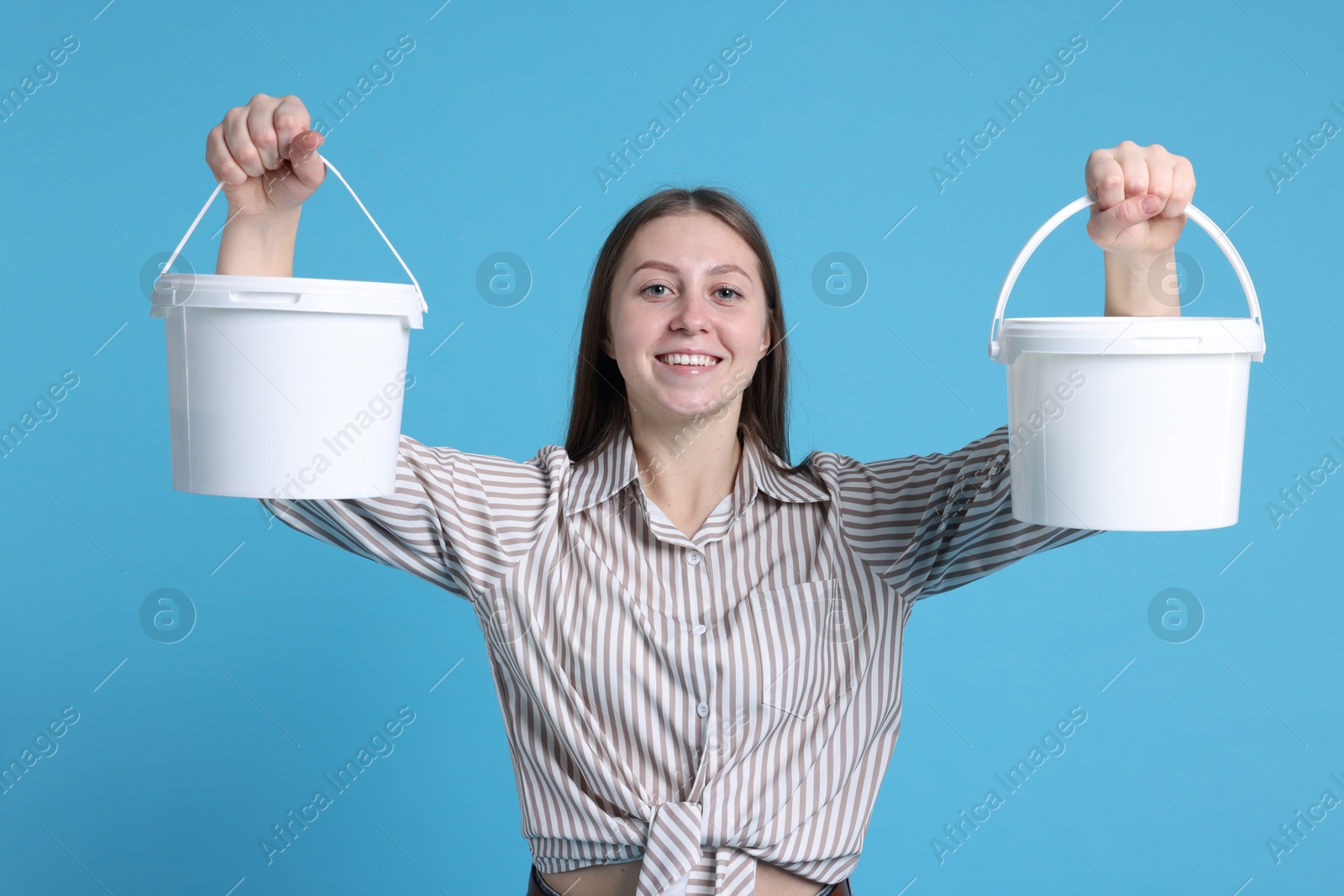 Photo of Woman with buckets of paint on light blue background