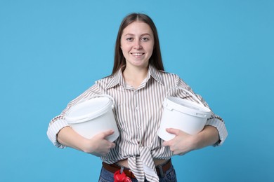 Photo of Woman with buckets of paint on light blue background