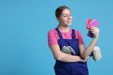 Photo of Professional painter with brush and color samples on light blue background. Space for text