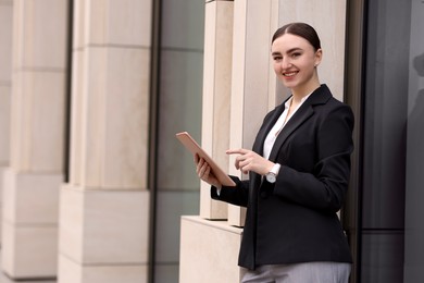 Photo of Woman in stylish formal suit with tablet outdoors. Space for text