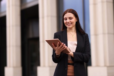 Photo of Woman in stylish formal suit with tablet outdoors. Space for text