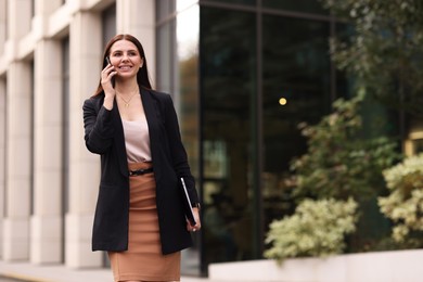 Photo of Woman in stylish formal suit talking on phone outdoors. Space for text