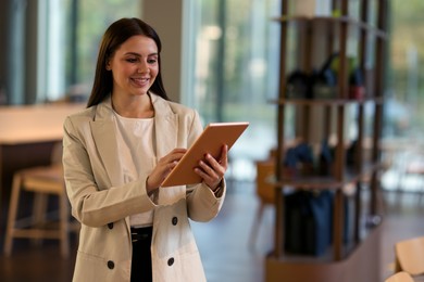 Photo of Woman in stylish formal suit with tablet indoors. Space for text