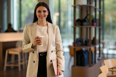 Photo of Woman in stylish formal suit with cup of coffee indoors. Space for text