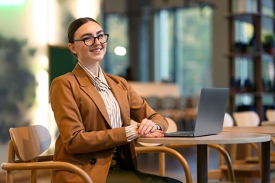 Photo of Woman in stylish formal suit working at table indoors