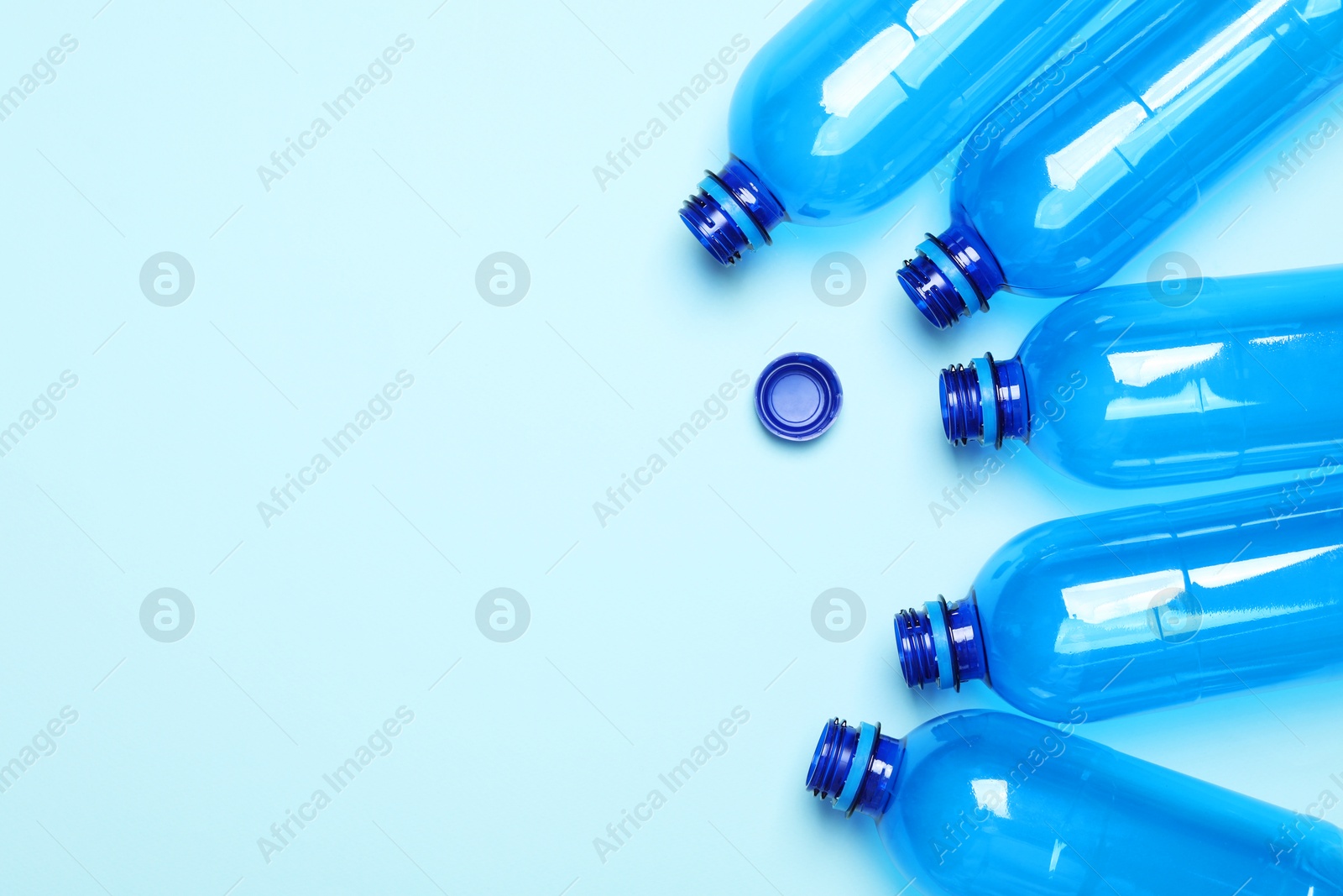 Photo of Empty plastic bottles on light blue background, flat lay. Space for text