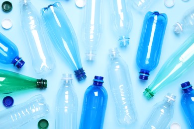 Photo of Empty plastic bottles on light blue background, flat lay