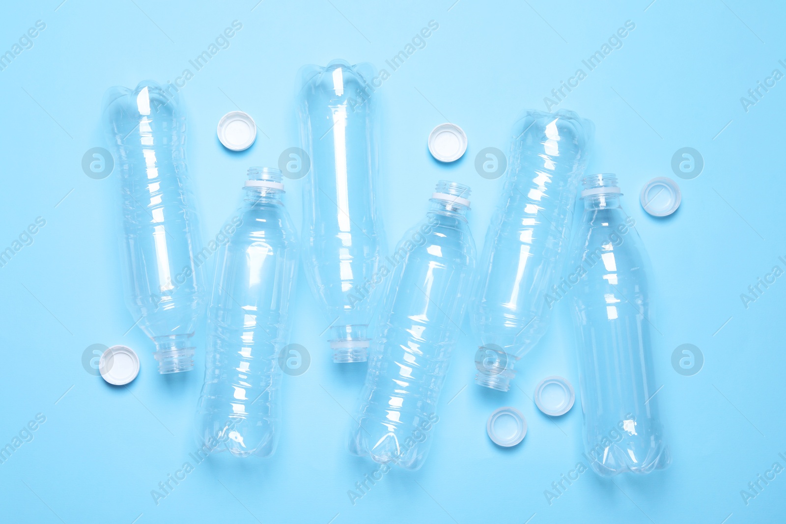 Photo of Empty plastic bottles on light blue background, flat lay