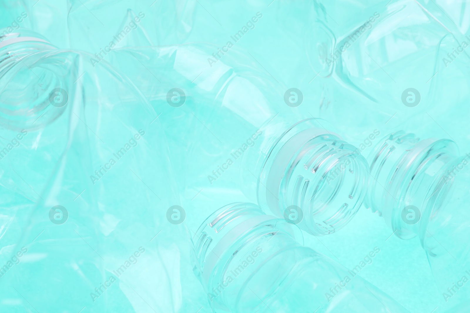 Photo of Crumpled plastic bottles on turquoise background, closeup