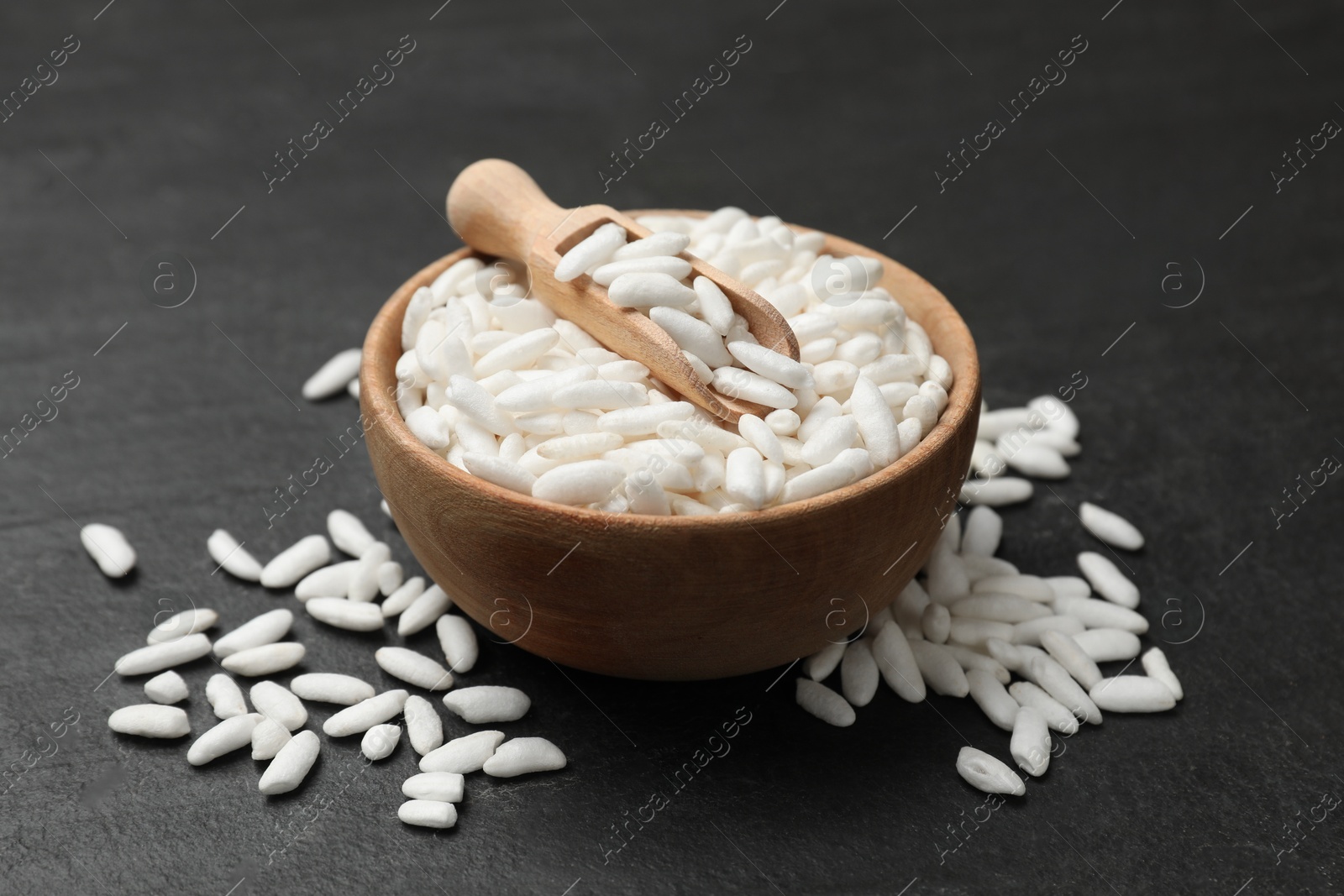 Photo of Puffed rice in bowl and scoop on dark table