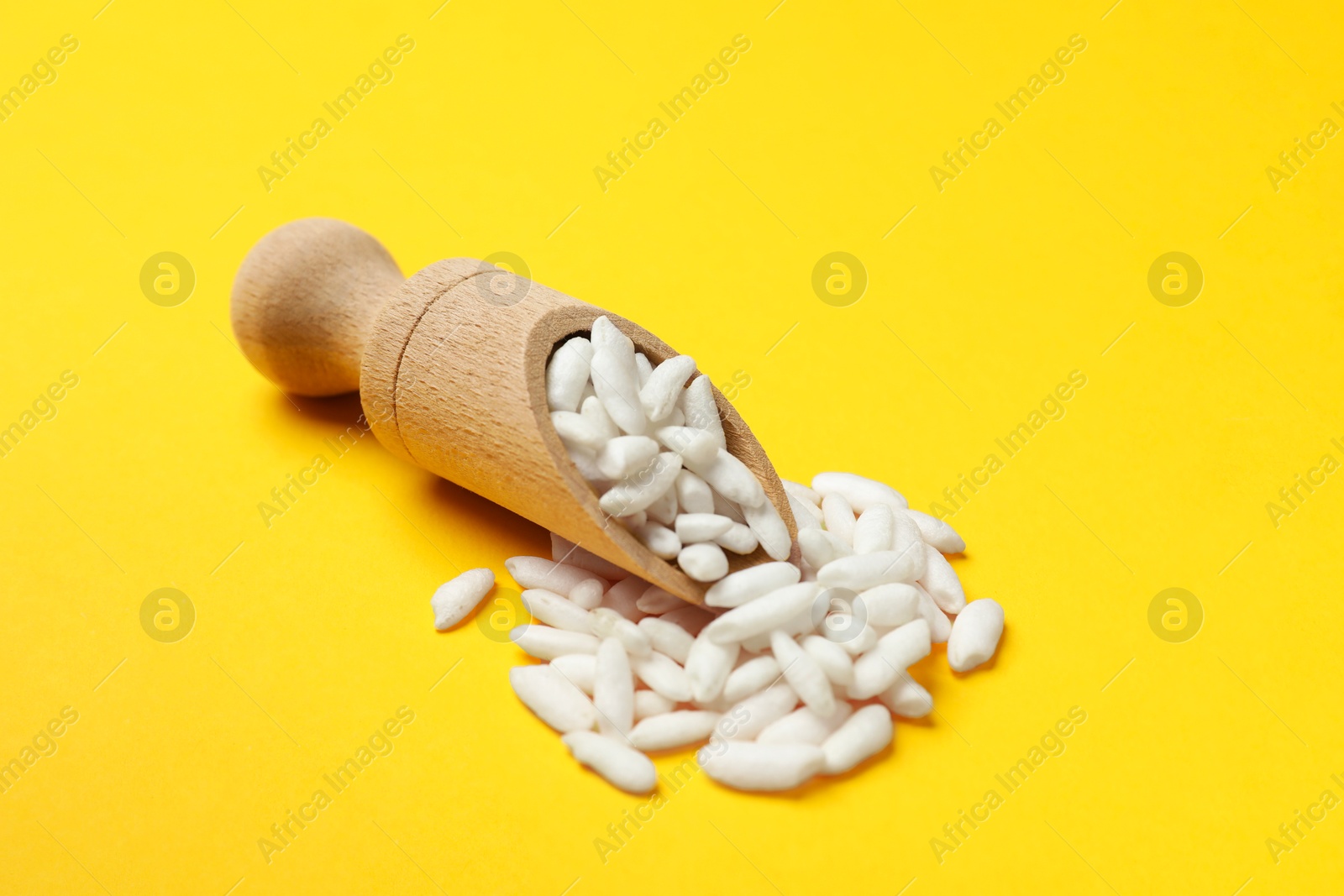 Photo of Scoop with puffed rice on yellow background, closeup