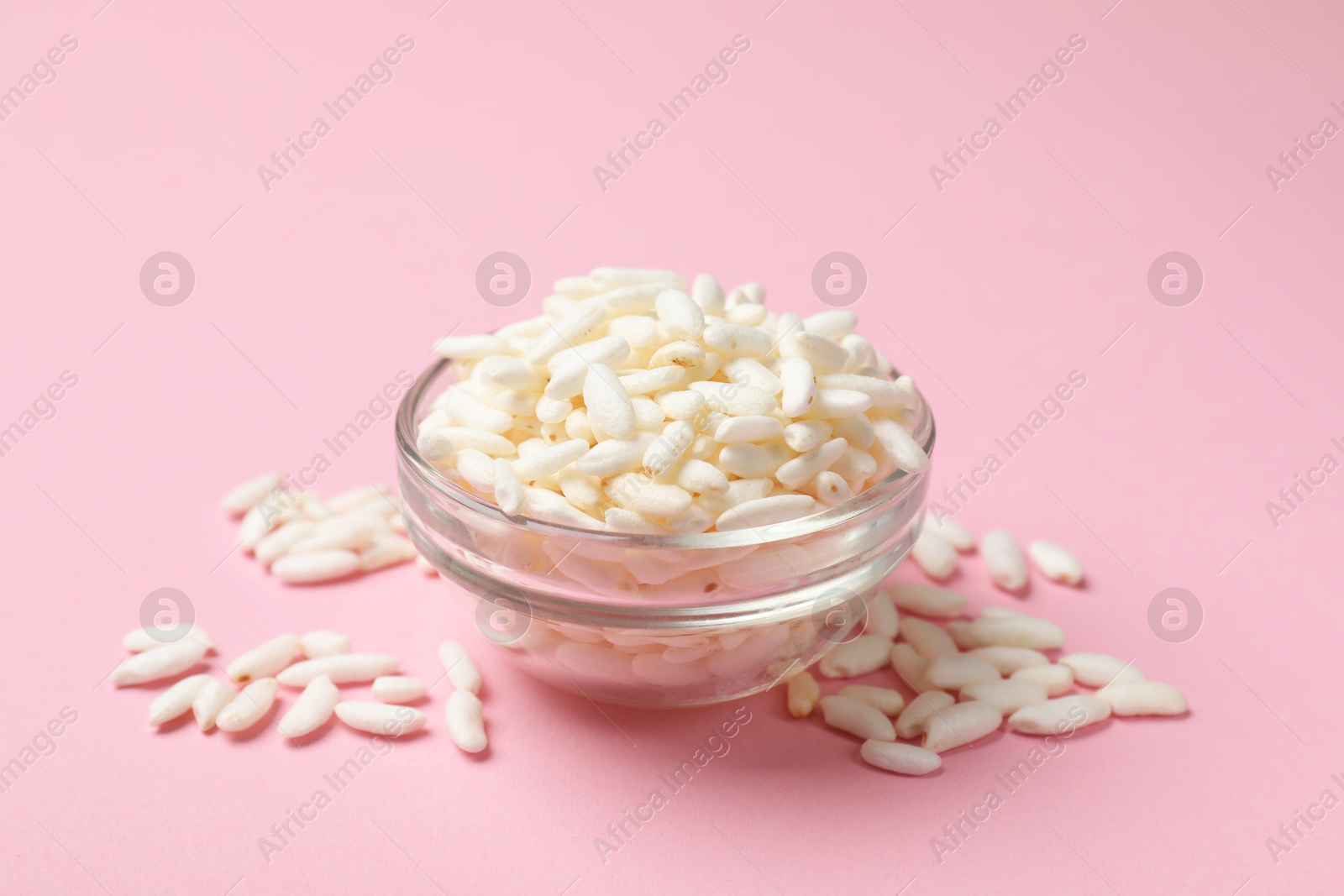 Photo of Puffed rice in bowl on light pink background, closeup