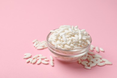 Photo of Puffed rice in bowl on light pink background, closeup