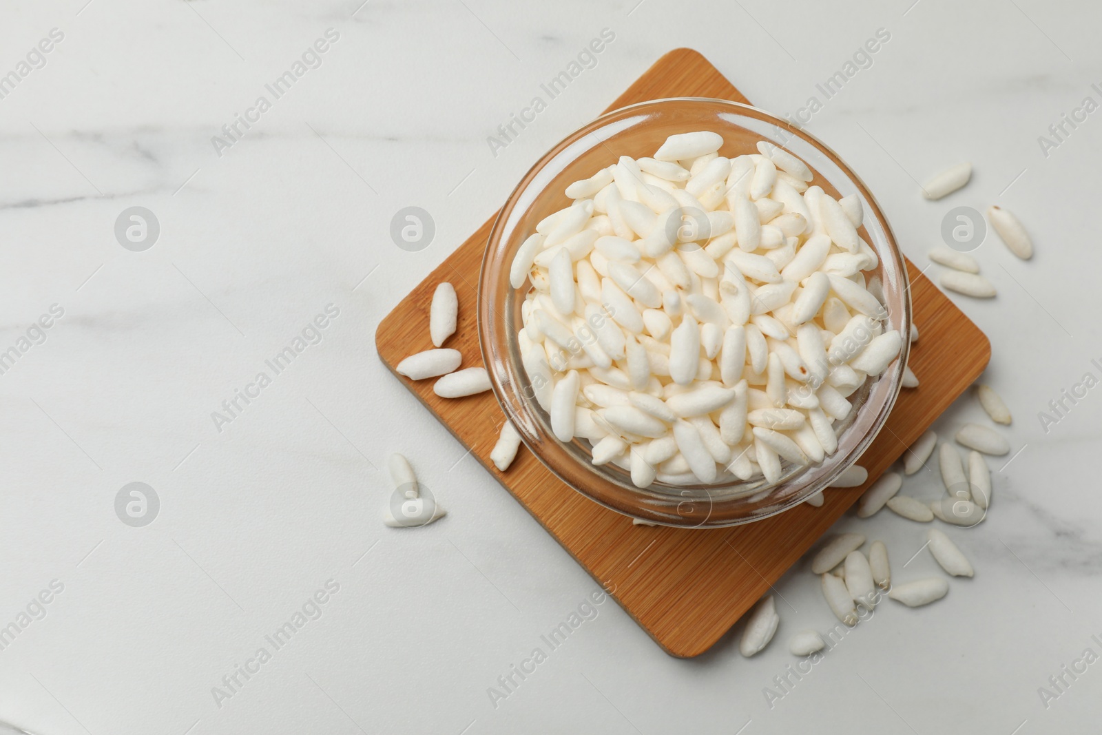 Photo of Puffed rice in bowl on white table, top view. Space for text