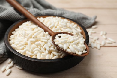 Photo of Puffed rice in bowl and spoon on white wooden table, closeup