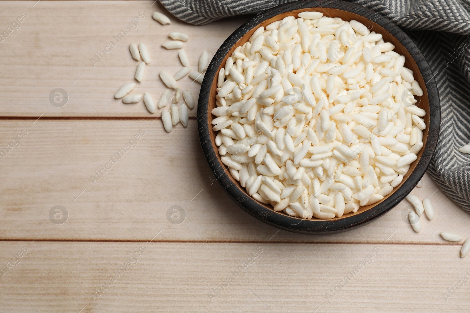 Photo of Puffed rice in bowl on white wooden table, flat lay. Space for text