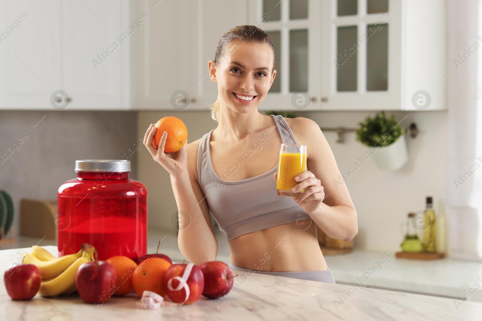 Photo of Weight loss. Happy woman with tasty shake and orange at white marble table in kitchen