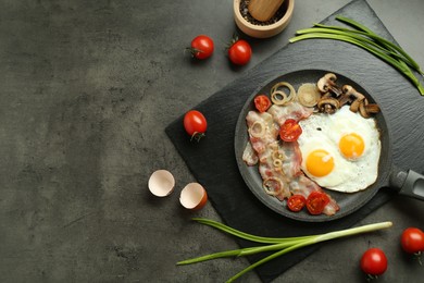 Photo of Tasty fried eggs, bacon and mushrooms served on grey table, flat lay. Space for text