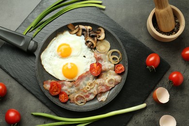 Photo of Tasty fried eggs, bacon and mushrooms served on grey table, flat lay