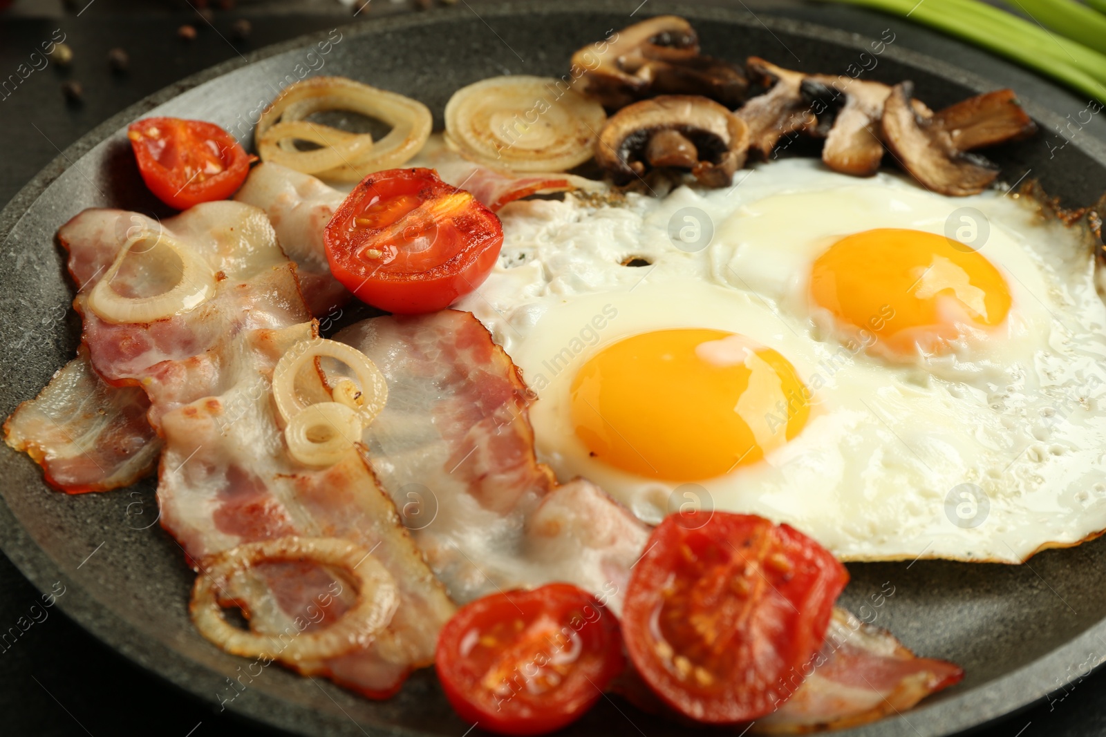 Photo of Tasty fried eggs, bacon and mushrooms on frying pan, closeup