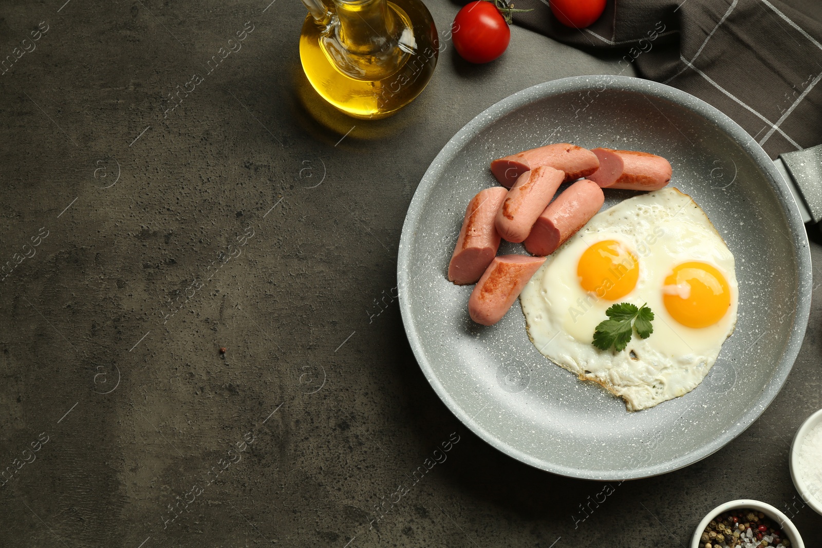 Photo of Tasty fried eggs and sausages served on grey table, flat lay. Space for text