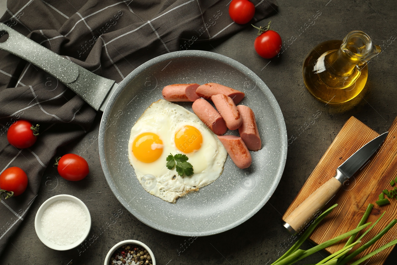 Photo of Tasty fried eggs and sausages served on grey table, flat lay