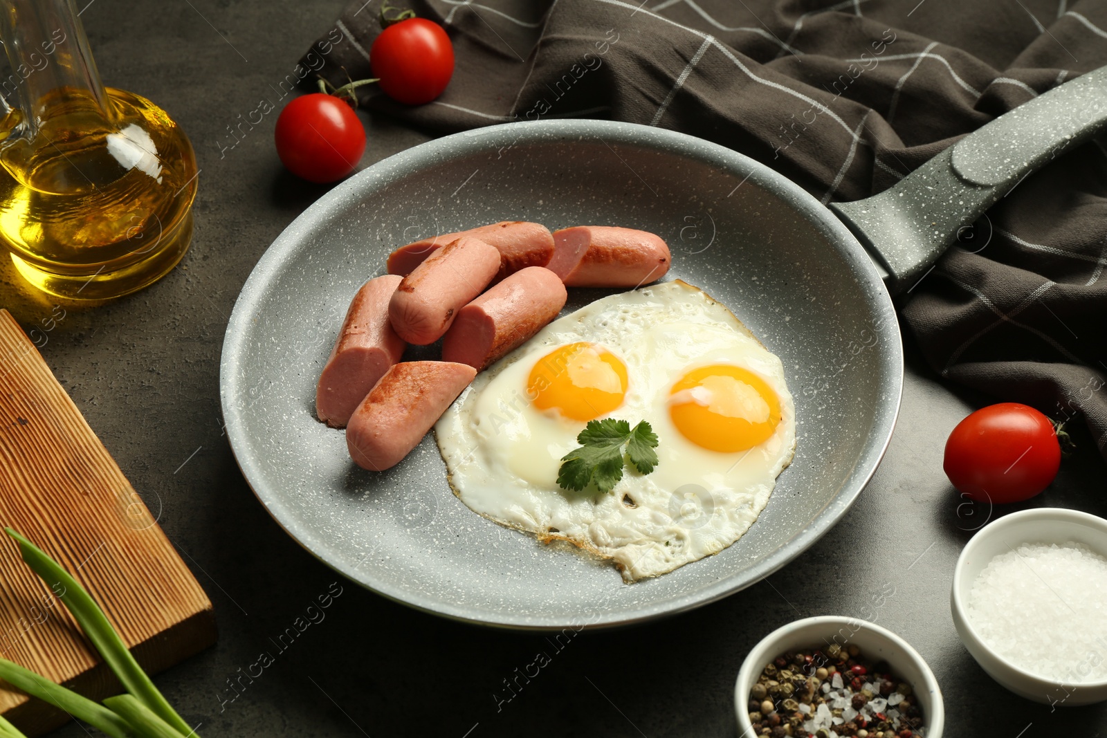 Photo of Tasty fried eggs and sausages served on grey table, closeup